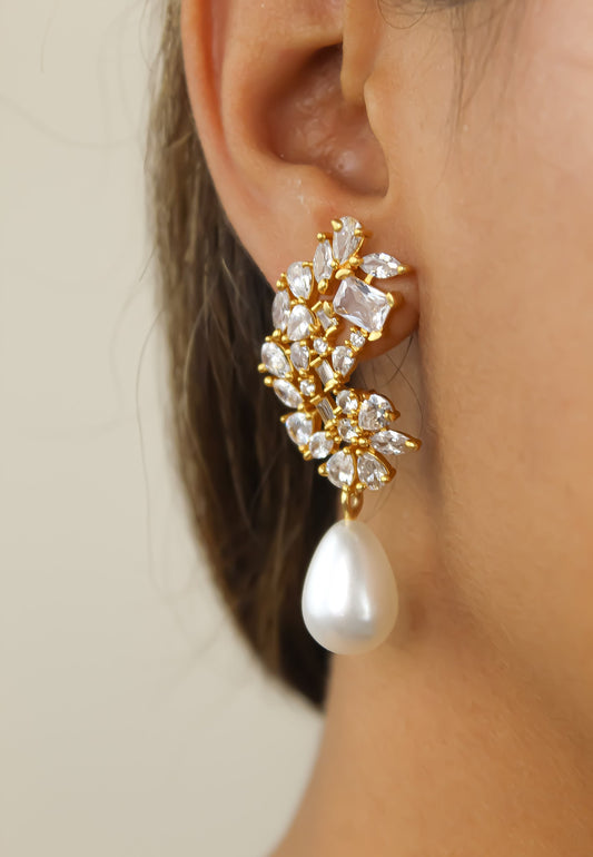 Close-up of the Pilar Golden Frosty Pearl Earrings in White worn by a model, highlighting the zirconia stones and resin pearl.